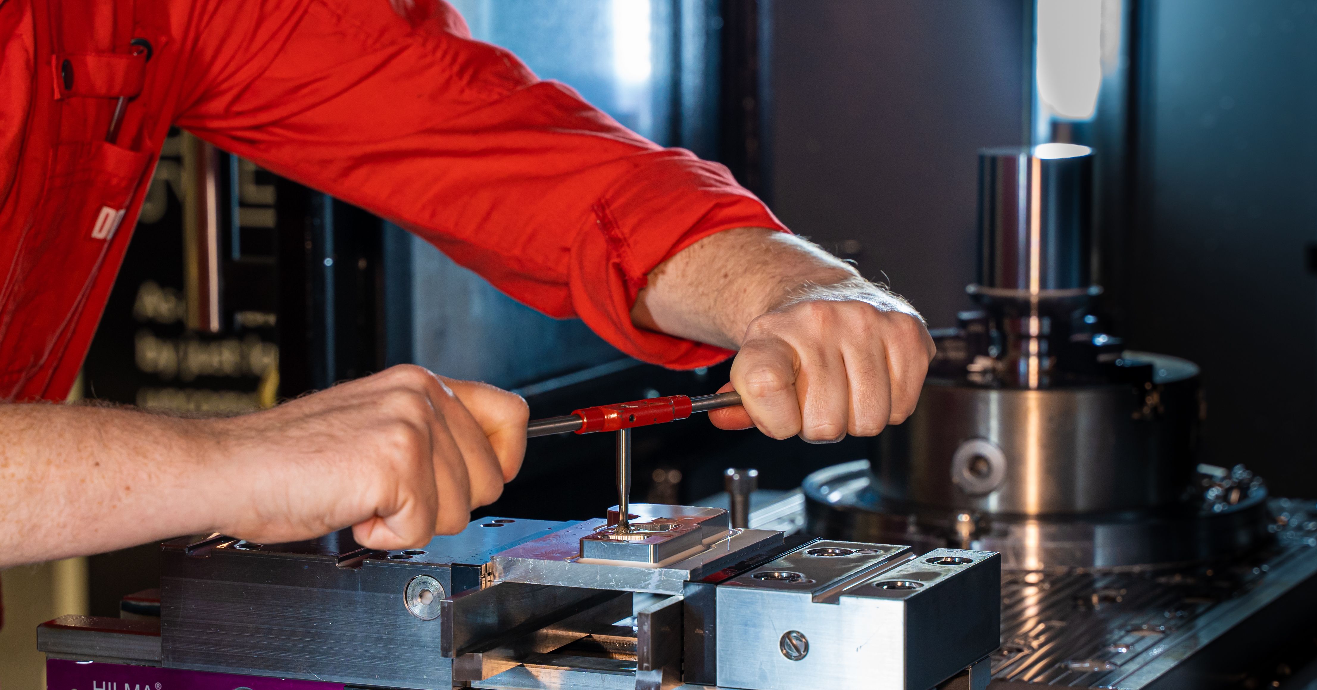 Technician tapping threaded holes in a machined metal workpiece